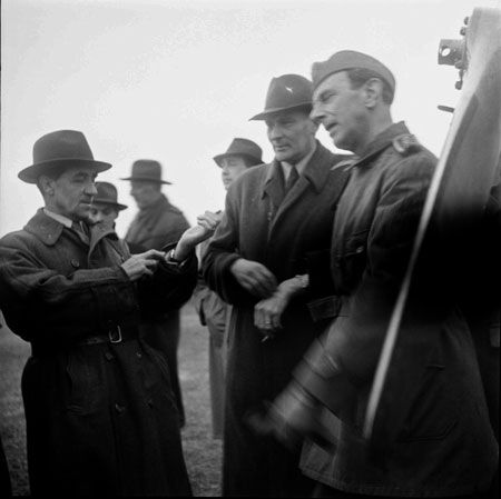 Yngve Ligner tittar på klockan. Bilsektionens E V Norman gör en frågande gest mot sin hand. Ivar af Sillén står t.h. i uniform. Foto: Åke Ahlstrand, Specialfoto