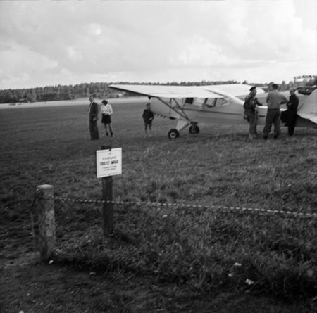 Ett par ses t.v. och Rune Hedlund står längst t.h. vid fenan. Mannen i basker bör vara flyglärare Henric Månsson. Foto: Åke Ahlstrand, Specialfoto