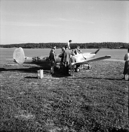 Ercoupe SE-AWU med Sörbyskogen i bakgrunden t.v. Claes Philip står på vingen och hälsar på någon. Foto: Åke Ahlstrand, Specialfoto