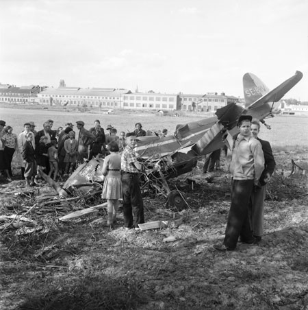 Karlskogas havererade Klemm vid Örebro. AVOS fabrik i bakgrunden. I mitten sticker Nikolaikyrkan upp sitt torn. Foto: Åke Ahlstrand, Specialfoto.