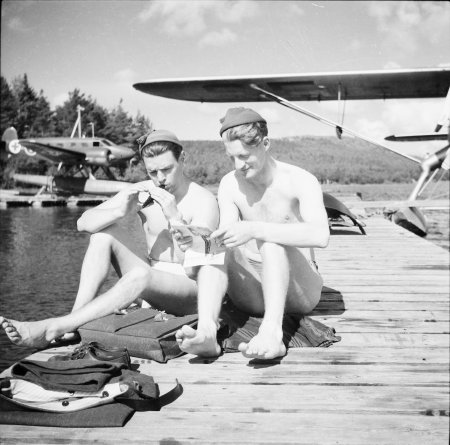 Arne Tengler t.h. framför Norrlandsflygs Norseman. Flygambulansen står på en flotte i bakgrunden t.v. Foto via Arne Tengler