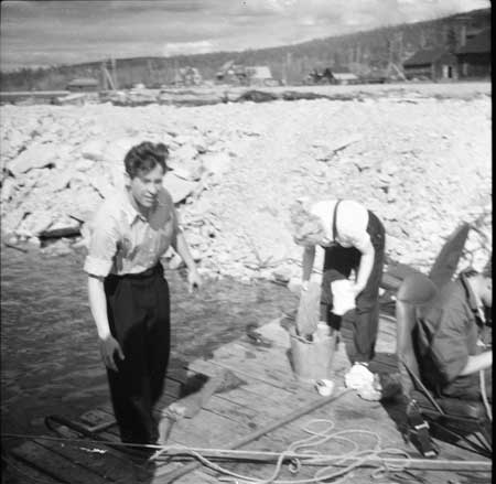 Piloten Tore Jonsing och städare på en flytbrygga. Porjus järnvägsstation syns i bakgrunden. Foto: Arne Tengler
